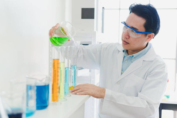 Asian scientists are preparing chemicals for testing and analysis in the laboratory. Scientists clear glasses and white shirts. Science and Chemistry Concept - Fotoğraf, Görsel