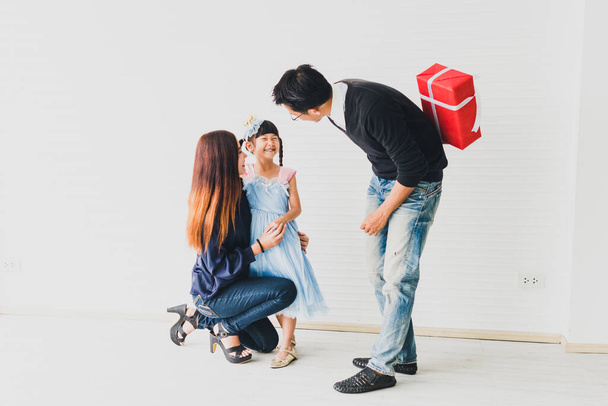 Asyalı anne ve baba, Noel ve yeni yıl arifesinde kızına kırmızı bir kutu hediye verir. Aile mutluluk zamanı konsepti.. - Fotoğraf, Görsel