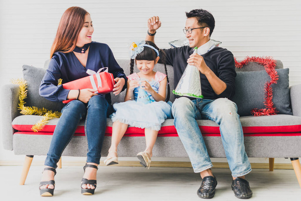 Father, mother and daughter are celebrating Christmas. Christmas hat and a gift for each other. Concept Asian family happiness time. - Photo, Image