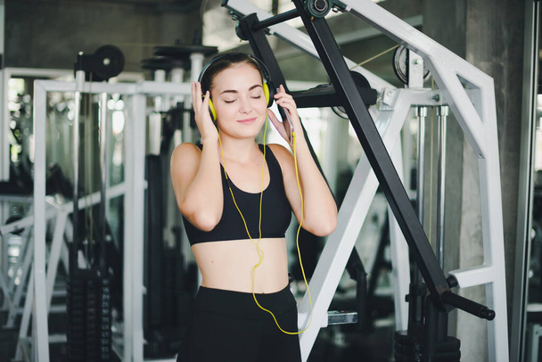 Beautiful women come to exercise in the gym and are relaxed by listening to music from headphones. She wears a sportswear. - Foto, imagen