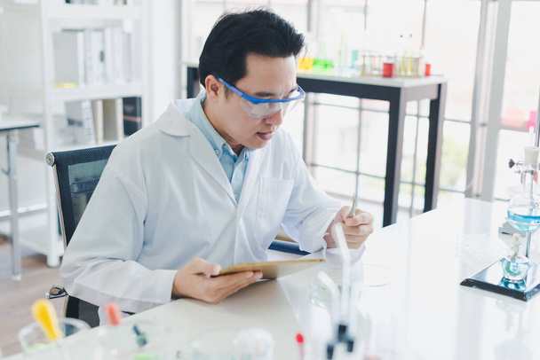 Asian scientists are preparing chemicals for testing and analysis in the laboratory. Scientists clear glasses and white shirts. Science and Chemistry Concept - Foto, immagini