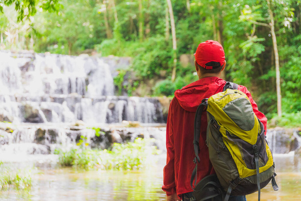 Счастливый рюкзак, прогуливающийся в осеннем лесу возле водопада. Тра
 - Фото, изображение
