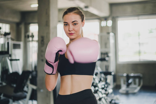 Beautiful girls exercise by boxing in the gym. She wears a pink boxing glove and wears exercise. - Foto, immagini