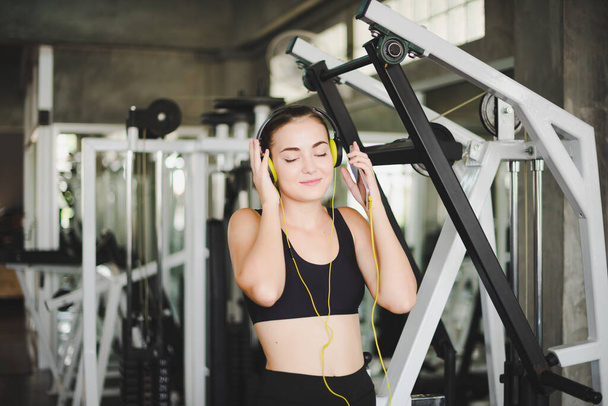 Beautiful women come to exercise in the gym and are relaxed by listening to music from headphones. She wears a sportswear. - Foto, Imagen