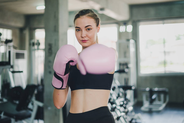 Beautiful girls exercise by boxing in the gym. She wears a pink boxing glove and wears exercise. - Foto, Bild