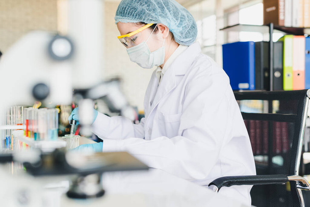 Asyalı bilim adamları laboratuvarda test ve analiz için kimyasallar hazırlıyorlar. Bilim adamları cam ve beyaz gömlekleri temizliyorlar. Bilim ve Kimya Konsepti - Fotoğraf, Görsel