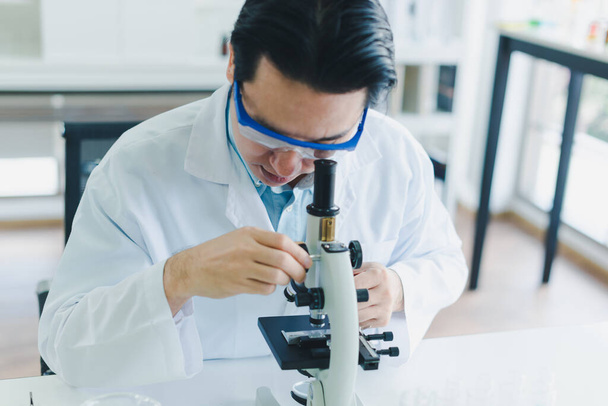 Asian scientists are preparing a microscope for laboratory testing and analysis. Science and Chemical Concepts. - 写真・画像