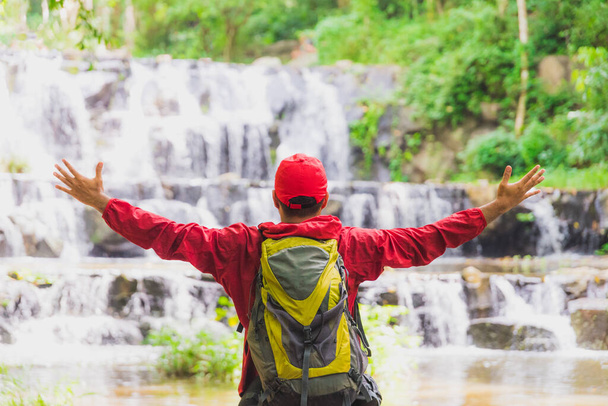 Szczęśliwy turysta wędrujący w jesiennym lesie w pobliżu wodospadu. Tra - Zdjęcie, obraz