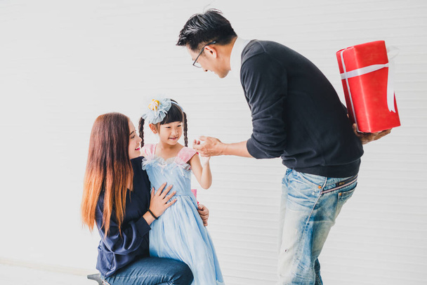 Père et mère asiatiques donnent un cadeau de boîte rouge à la fille à la veille de Noël et du jour de l'An.
. - Photo, image