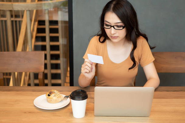 女性はクレジットカードでオンラインショッピング,女性はノートパソコンでインターネットを閲覧;中小企業の概念,電子決済,電子マネーウォレットや財布,オンラインショッピング - 写真・画像