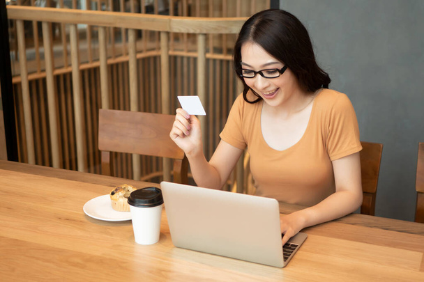 onnellinen hymyilevä nainen ostoksia verkossa luottokortilla, nainen selaamassa internetiä kannettavalla tietokoneella; käsite sähköisen maksun, e-maksu, digitaalisen rahan lompakko tai käsilaukku, verkkokaupoissa
 - Valokuva, kuva