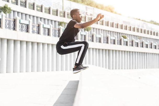 Athletic young afroamerican man running on the promenade. Black Male runner sprinting outdoors. Healthy lifestyle concept. - 写真・画像