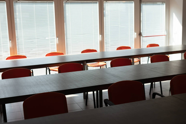 Secretárias vazias e cadeiras em uma sala de escritório deserta sem pessoas durante a pandemia do vírus da corona
. - Foto, Imagem