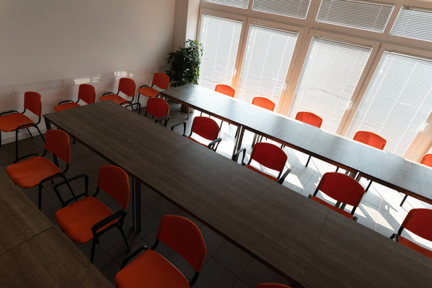 Empty desks and chairs in a conference room with no people during corona virus pandemic. - Photo, Image