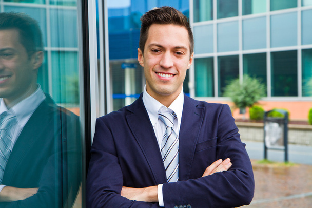 Smiling young businessman standing outside a building - 写真・画像