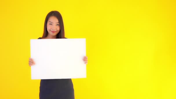 felvétel gyönyörű ázsiai nő kezében üres papírt elszigetelt sárga - Felvétel, videó