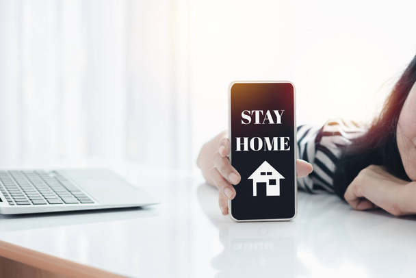 Frauenhand-Smartphone mit Warnmeldung für Selbstquarantäne, soziale Distanzierung, Verbleib und Arbeit zu Hause bei Coronavirus oder Covid-2019-Ausbruchssituation - Foto, Bild