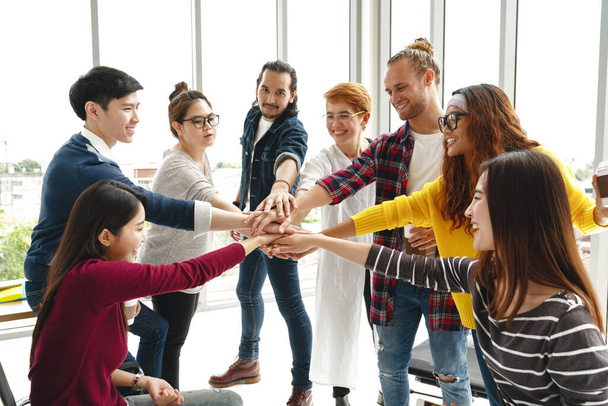 Multiethnic young team stack hands together as trusted unity and teamwork in modern office. Diverse group togetherness collaboration or friends huddle concept. Power of startup business team building. - Photo, Image