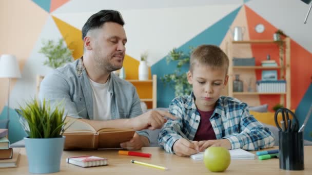 Loving dad reading book to adorable kid who drawing pictures in apartment - Metraje, vídeo