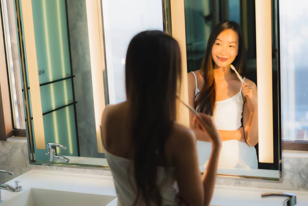 Portrait beautiful young asian woman brushing teeth in bathroom interior - Fotografie, Obrázek
