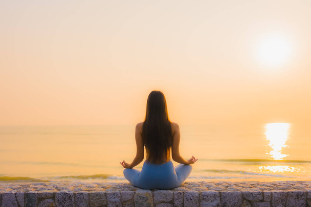 Portret młoda azjatycka kobieta robi medytację wokół morza ocean plaży o wschodzie słońca dla zdrowia - Zdjęcie, obraz