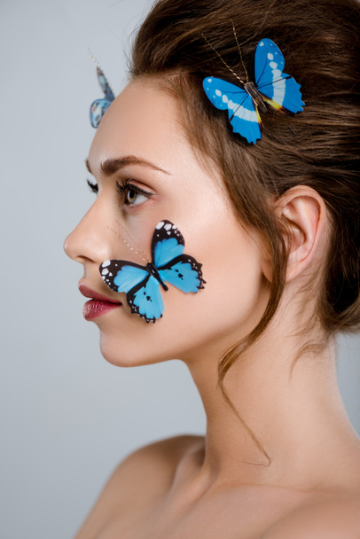 atractiva mujer con mariposas decorativas azules en la cara aislada en gris
  - Foto, Imagen