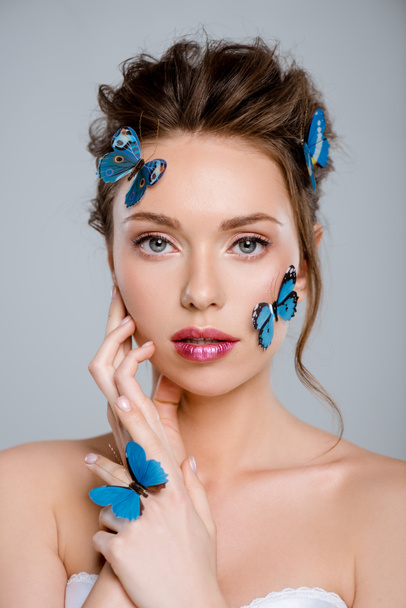 attractive woman with blue decorative butterflies on face looking at camera isolated on grey  - Fotoğraf, Görsel