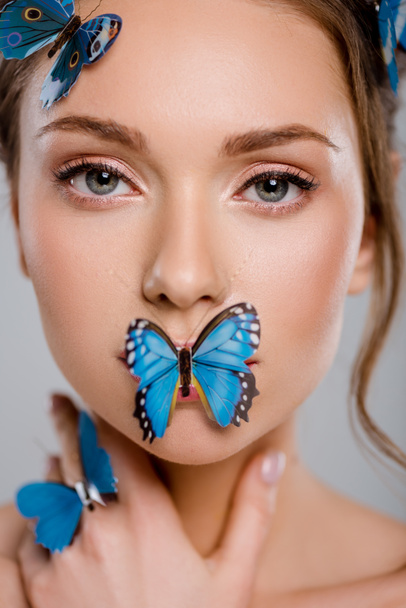 close up attractive young woman with decorative butterflies on face isolated on grey  - Fotografie, Obrázek