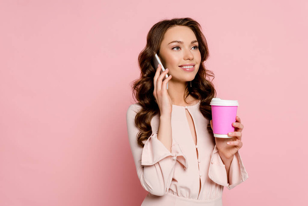 happy girl talking on smartphone and holding paper cup on pink  - Zdjęcie, obraz