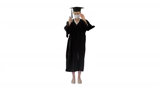 Φοιτητής αποφοίτησης με ιατρική μάσκα χρησιμοποιώντας απολυμαντικό σε λευκό φόντο. - Πλάνα, βίντεο