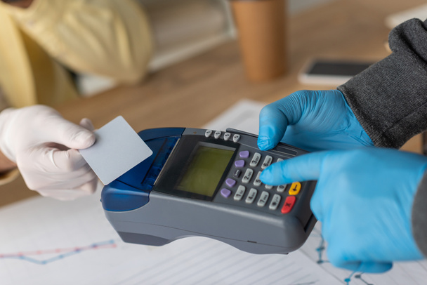 vista cortada do homem de negócios segurando cartão de crédito perto do homem de entrega com terminal de pagamento
 - Foto, Imagem