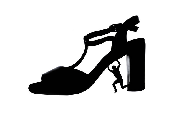 Feminizm, kadın ayakkabısı altındaki bir adam, soyutlanmış siluet çizgisi.. - Fotoğraf, Görsel