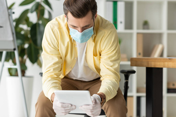 homme d'affaires en masque médical et gants en latex en utilisant une tablette numérique au bureau
 - Photo, image