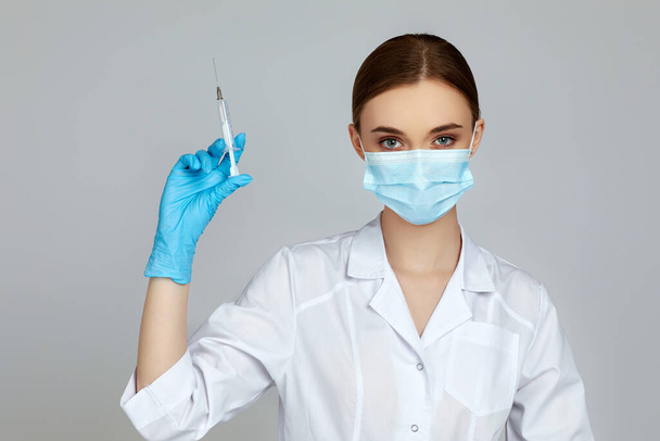 woman doctor holding syringe on gray background. - Φωτογραφία, εικόνα