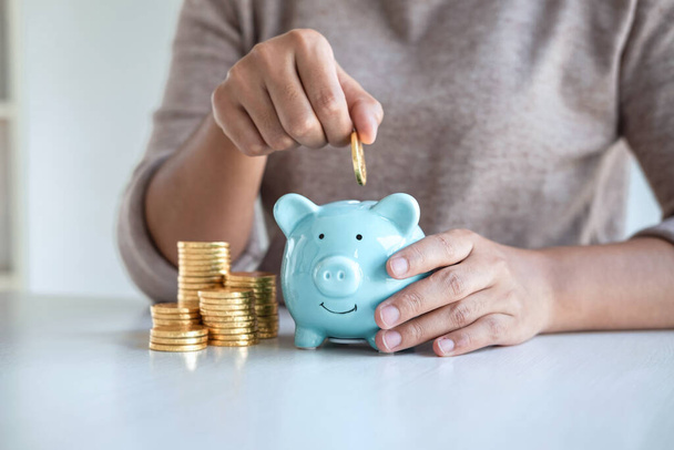 Young woman putting coins into piggy bank planning growing saving to strategy with money box for future plan fund of travel, education, home and retirement. - Photo, Image