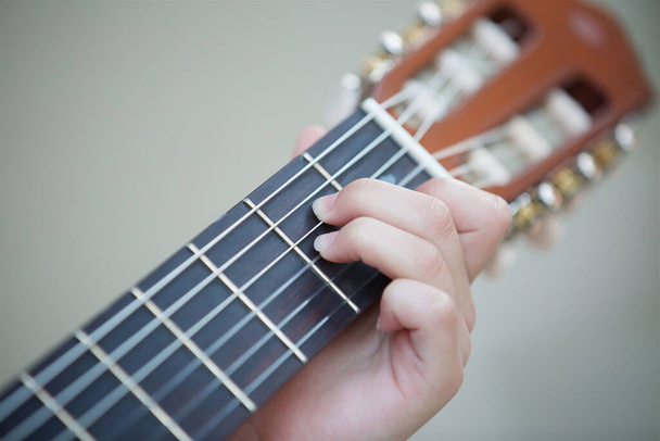 La mano de una adolescente acostada en las cuerdas de una guitarra instrumento musical. El concepto de cultura y arte
. - Foto, Imagen