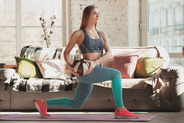 Mujer joven que enseña en casa cursos en línea de fitness, aeróbico, estilo de vida deportivo mientras está en cuarentena
 - Foto, imagen