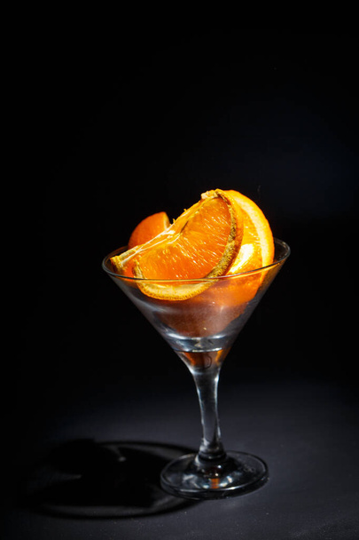 Fresh oranges sliced in slices in a glass on a black background - Foto, immagini