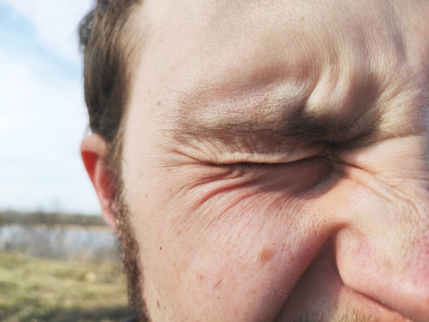Os olhos masculinos franzem a testa do sol. Rugas faciais masculinas
 - Foto, Imagem