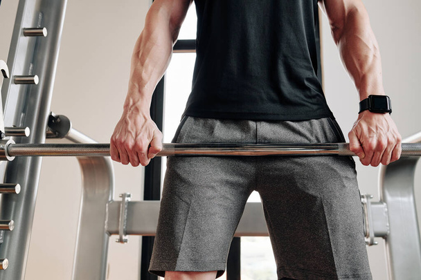 Обрезанный образ сильного здоровяка, поднимающего штангу в спортзале и делающего румынскую тягу
 - Фото, изображение