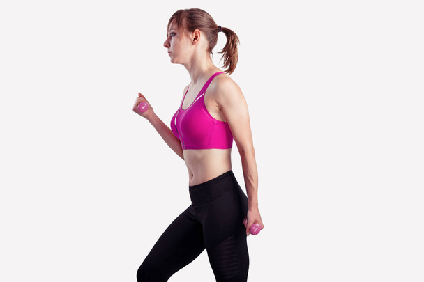 Mulher desportiva faz os exercícios com halteres em fundo cinza. Foto de mulher musculosa em sportswear no estúdio
 - Foto, Imagem