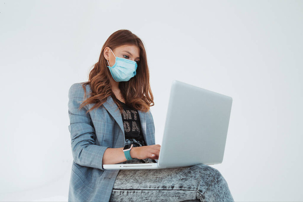 Девушка в защитной маске работает на ноутбуке
 - Фото, изображение