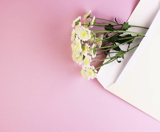 envelope with a bouquet of daisies on a pink background. white greeting card envelope with flower bouquet - Foto, imagen