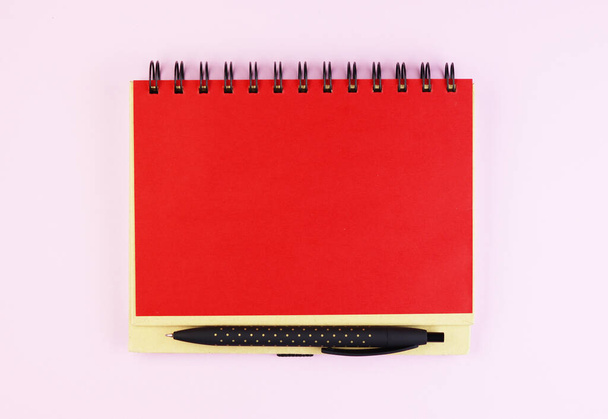 sauberer roter Notizblock und schwarze Stiftoberseite. ein rotes Notizbuch auf rosa Hintergrund - Foto, Bild