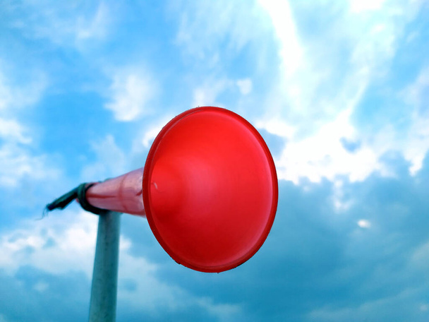 un lazo de cuerno de plástico rojo con un tubo de plástico blanco con fondo de cielo azul
 - Foto, Imagen