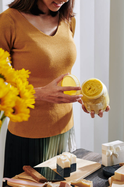 石鹸作りのための高品質の蜂ワックスの創造的な若い女性のオープニング瓶 - 写真・画像