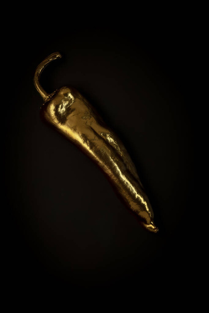 Golden pepper on a black background, stylish minimalistic composition with copyspace - Foto, afbeelding