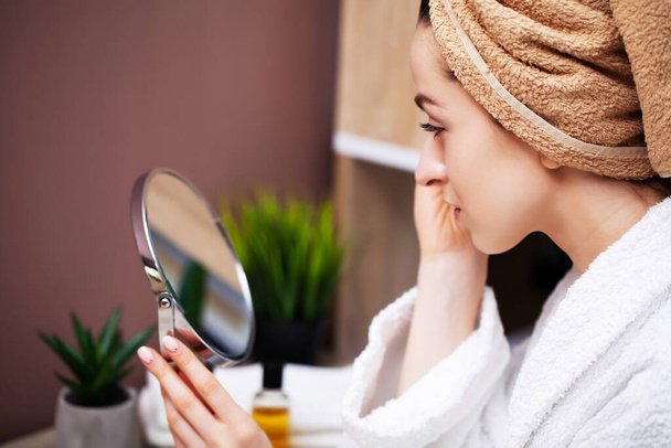 Linda chica en el baño haciendo procedimiento cosmético para el cuidado de la piel facial
. - Foto, Imagen