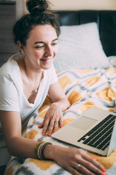 Egy fiatal nő online beszél, arccal a laptopon. Szórakoztató hangulat. Boldog reggelt Örömteli kommunikáció rokonokkal és barátokkal az interneten. Érzelmek kifejezése. Maradj otthon!. - Fotó, kép