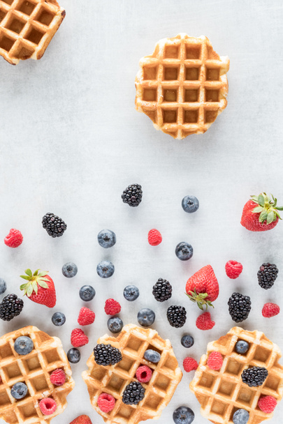 A top down vertical view of an abstract arrangement of Belgian waffles and mixed berries. - Photo, Image